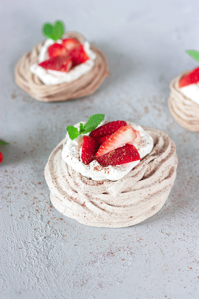 close up chocolate meringue nest with whipped cream and strawberries
