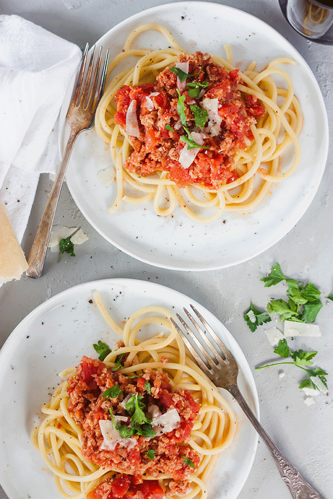 overhead bucatini all'amatriciana on white plate, antique forks on plate and parsley garnish